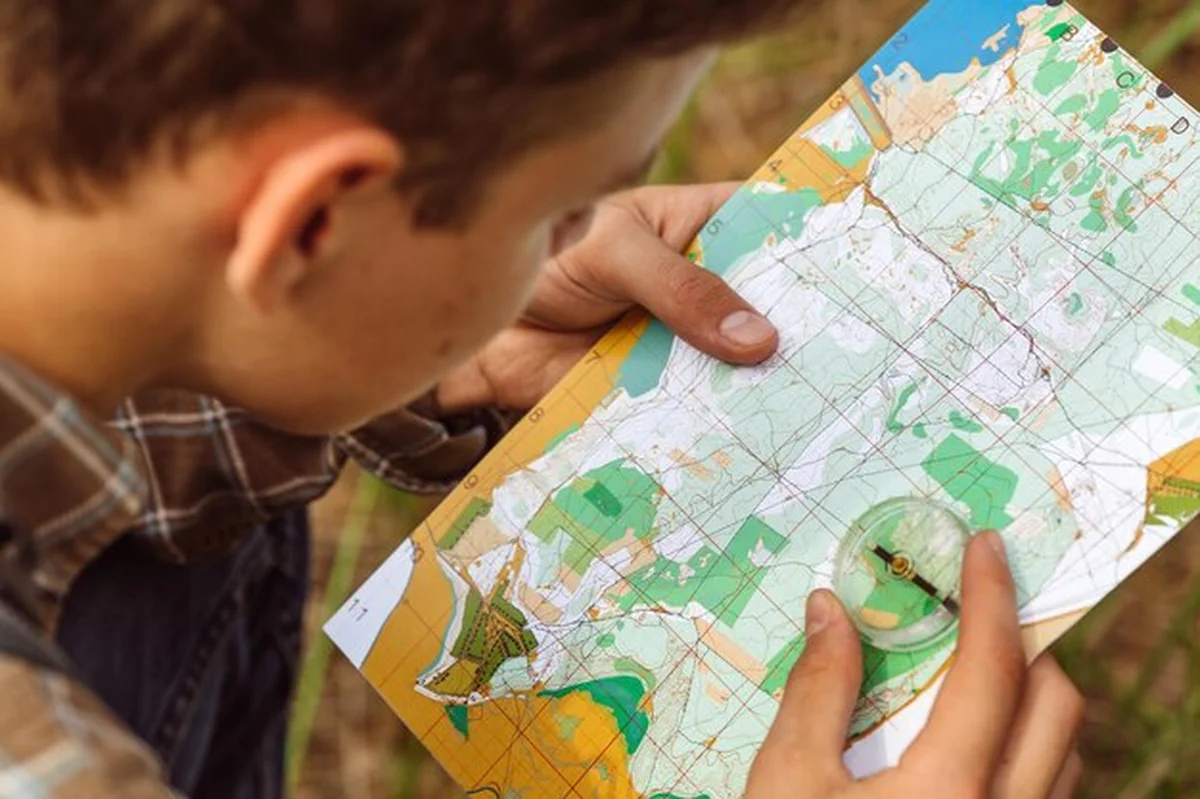 Turysta ustala trasę na mapie i kompasie
