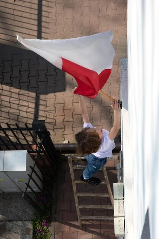 Chłopiec wywiesza polską flagę 3 Maja